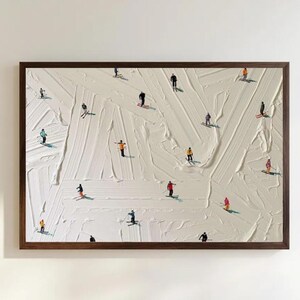 Op de afbeelding: Een ingelijst rechthoekig schilderij met een getextureerd wit impasto-oppervlak, waarop talloze kleine figuren van skiërs in kleurrijke winterkleding verspreid over het doek staan, elk geplaatst op individuele skisporen in de sneeuw.