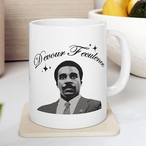 May include: White ceramic mug with a black and white image of a man with the text "Devour Excellence" in a black cursive font.