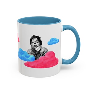 Puede incluir: Taza de cerámica blanca con interior y asa azules. La taza presenta una imagen en blanco y negro de una persona fumando, rodeada de ilustraciones de nubes de colores. Un diseño único y artístico.