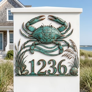 May include: A rectangular house number plaque featuring the digits 1236 in a verdigris patina finish. The design includes a central crab, cattails, and seashells, all rendered in a weathered teal and bronze metal tone against a white background.