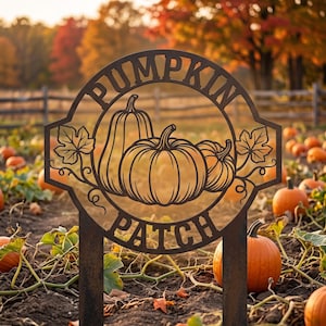 以下が含まれることがあります： PUMPKIN PATCHという文字が刻まれた円形のフレームを持つ、ダークブラウンの金属製ガーデンステーク。円の内側には、葉や蔓を伴う3つのカボチャのシルエットが切り抜かれており、2本の垂直な金属製の支柱で支えられています。
