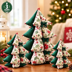 May include: Three fabric Christmas tree decorations in varying sizes. Each tree is constructed from stuffed triangular segments in solid dark green and a cream-colored fabric featuring a red poinsettia and green foliage print. Small dark green bows and white beads accent the trees.
