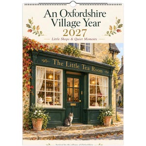 May include: A 2027 wall calendar titled An Oxfordshire Village Year: Little Shops & Quiet Moments. The cover features a dark green storefront labeled The Little Tea Room, with white curtains, potted plants, and a cat sitting by the door.