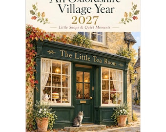 May include: A 2027 wall calendar titled An Oxfordshire Village Year: Little Shops & Quiet Moments. The cover features a dark green storefront labeled The Little Tea Room, with white curtains, potted plants, and a cat sitting by the door.