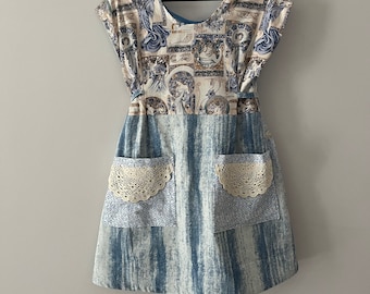 May include: A blue and white dress with a floral print and lace trim on the pockets. The dress has a scoop neck and short sleeves.