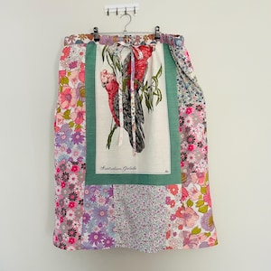 May include: A long, patchwork skirt with a floral print. The skirt has a green panel with a white bird illustration and the text "Australian Galahs".