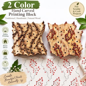 May include: Two square wooden printing blocks with hand-carved patterns featuring small holes and raised textures. One block has dark brown carved details, while the other features red accents. A piece of fabric displays a printed red and black floral pattern.