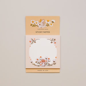 May include: A pack of sticky notes featuring a cute cartoon bunny surrounded by daisies. The notes are made in the USA and have the text "Thousand Skies Sticky Notes" on the front.
