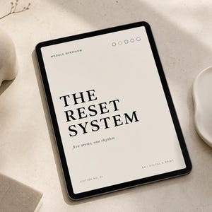 Puede incluir: Una tableta que muestra un documento titulado THE RESET SYSTEM, five areas, one rhythm, edition no. 01, A4 / digital & print. La pantalla presenta un fondo beige con texto negro, colocada cerca de un jarrón de cerámica y una taza blanca.