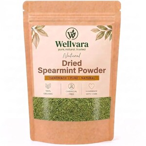Può includere: Una busta verticale color marrone chiaro contenente polvere di menta essiccata. L'etichetta riporta il logo Wellvara, il testo Natural Dried Spearmint Powder e icone che indicano 100% biologico, senza sostanze chimiche e fatto a mano. Una finestra mostra la polvere.