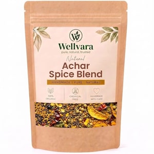 May include: A brown paper pouch containing Achar Spice Blend by Wellvara. The label features the text Natural Achar Spice Blend, Handmade, Pure, Natural, 100% Organic, Chemical Free, and Handmade with Care, with a visible mix of dried spices.