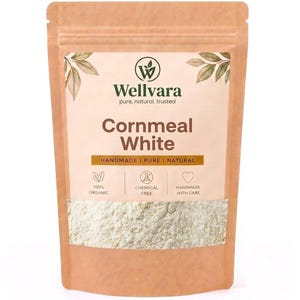 Op de afbeelding: Een lichtbruine stazak met witte maïsmeel. Het etiket bevat het Wellvara-logo, de tekst Cornmeal White en iconen voor 100% biologisch, chemievrij en handgemaakt met zorg. De verpakking heeft een doorzichtig venster aan de onderzijde.