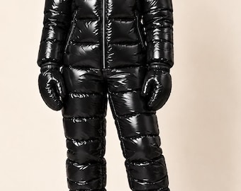 May include: A glossy black one-piece snowsuit featuring a high-shine finish, a full-length front zip, a hood, and horizontal quilted padding. The outfit includes matching black mittens and black boots, creating a cohesive, insulated look.