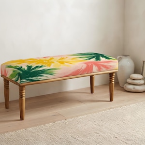 May include: A rectangular bench with four turned wooden legs and a cushioned seat featuring a vibrant, abstract pattern of yellow, green, and pink brushstrokes on a light background. The bench has a natural wood finish on the frame.