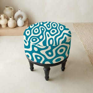 May include: A round ottoman featuring a teal and cream abstract wavy pattern on the upholstered seat. The base consists of four dark brown wooden legs with a turned design, providing a stable foundation for the circular cushioned top.