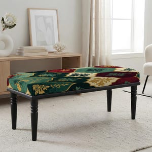 May include: A rectangular bench featuring a cushioned seat upholstered in a dark green, red, and gold damask-style patterned fabric. The bench is supported by four black, turned wooden legs that provide a stable base for the seat.