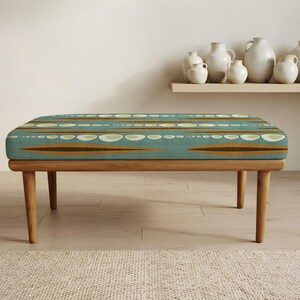 May include: A rectangular bench with four tapered wooden legs and a cushioned seat upholstered in a teal fabric featuring a repeating pattern of horizontal brown stripes and light green oval shapes arranged in rows across the entire surface.