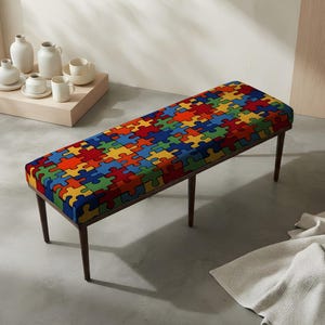 May include: A rectangular bench featuring a vibrant, multi-colored puzzle piece pattern in red, blue, yellow, and green on the upholstered seat. The bench is supported by four slender, dark brown wooden legs that taper toward the floor.