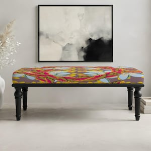 May include: A rectangular bench featuring a dark brown upholstered seat with a vibrant floral pattern in shades of red, yellow, and light blue. The bench is supported by four black, turned wooden legs that provide a sturdy base for the seat.
