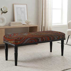 May include: A rectangular bench featuring a cushioned seat with a multi-colored agate-inspired pattern in shades of red, orange, gray, and black. The bench is supported by four slender, turned black wooden legs that provide a stable base.