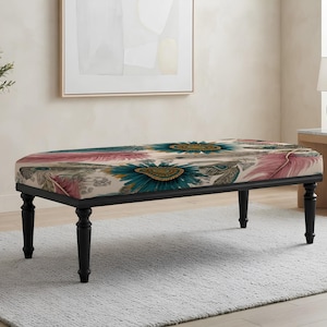 May include: A rectangular upholstered bench featuring a cream-colored fabric top with a vibrant pattern of large teal flowers and soft pink feathers. The bench is supported by four turned, matte black wooden legs that provide a sturdy base.
