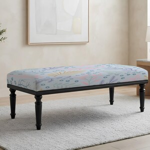 May include: A rectangular bench featuring a light blue upholstered seat with a multi-colored botanical pattern of pink, yellow, and dark blue shapes. The bench is supported by four black wooden legs with a turned, spindle-style design.