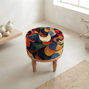 May include: A round ottoman featuring a vibrant, multi-coloured abstract pattern with swirling shapes in shades of red, blue, orange, yellow, and dark green. The seat is supported by four short, light-coloured wooden legs with a turned, rounded design.