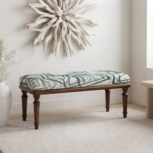 May include: A rectangular bench featuring a dark brown wooden frame with four turned legs and a cushioned seat upholstered in a white fabric with a dark green geometric line pattern that creates an abstract, angular design across the surface.