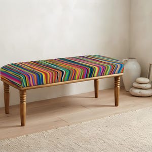 May include: A rectangular bench featuring a cushioned seat upholstered in a vibrant, multi-colored fabric with thin, vertical wavy stripes in shades of blue, red, yellow, green, and purple, supported by four turned wooden legs in a light brown finish.