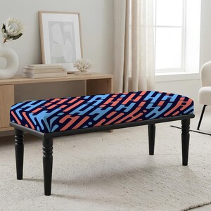 May include: A rectangular bench featuring a dark blue upholstered seat with a repeating pattern of light blue and coral-colored abstract shapes. The bench is supported by four turned black wooden legs that provide a stable base for the seat.
