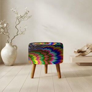 May include: A round ottoman featuring a vibrant, multi-colored fractal pattern with swirling hues of blue, green, yellow, and magenta. The seat is supported by three light-toned wooden legs, providing a stable base for this circular piece of furniture.