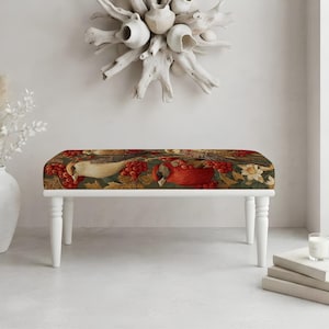 May include: A rectangular bench featuring a dark green fabric upholstery with a detailed print of red cardinals, berries, and white flowers. The bench is supported by four white, turned wooden legs that provide a sturdy base for the seat.