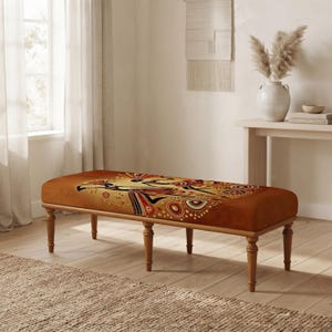 May include: A rectangular upholstered bench with four tapered wooden legs. The seat features a warm brown fabric base decorated with a detailed, multi-coloured graphic print of stylised figures and circular patterns in shades of red, black, and gold.