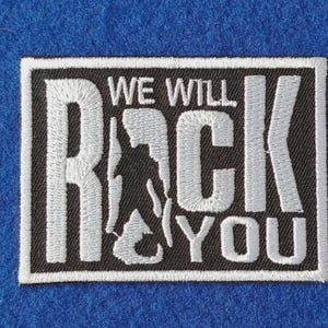 May include: A rectangular embroidered patch with a black background and a white border. The text reads WE WILL ROCK YOU in white, with the letter O replaced by a white silhouette of a creature resembling Bigfoot standing in profile.