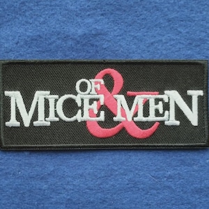 May include: A rectangular embroidered patch with a black background. The text OF MICE & MEN is stitched in white capital letters, with a large, stylised pink ampersand symbol positioned behind the word OF and between the words MICE and MEN.