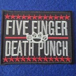 May include: A rectangular black embroidered patch featuring the white text FIVE FINGER DEATH PUNCH. A white brass knuckle icon with the letters FFDP is centred between the words. Rows of small red stars border the top and bottom edges.