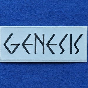 Peut inclure: Un écusson rectangulaire brodé présentant le mot GENESIS en fil noir sur un fond en tissu blanc. Le lettrage utilise une police stylisée et angulaire avec des lignes géométriques nettes. L'écusson possède une bordure cousue propre.