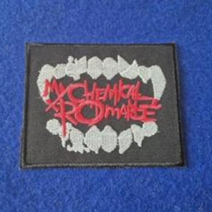 May include: A rectangular black embroidered patch featuring a stylized set of white teeth forming a circular border. Centered within the teeth is the text My Chemical Romance stitched in bold red thread with a distinct, jagged font style.