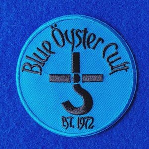 Può includere: Una toppa ricamata circolare con sfondo blu brillante e cuciture nere. Il testo Blue Oyster Cult è arcuato nella parte superiore, con il simbolo della band al centro e il testo EST. 1972 ricamato in nero nella parte inferiore.