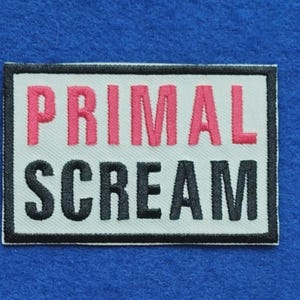 Puede incluir: Un parche rectangular bordado con fondo blanco y un borde negro grueso. El texto PRIMAL está bordado en letras mayúsculas rosas en la línea superior, y la palabra SCREAM está bordada en letras mayúsculas negras en la línea inferior.