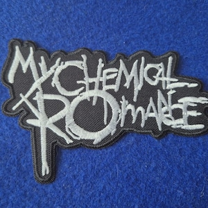May include: A black embroidered patch featuring the white text My Chemical Romance in a stylised, jagged font. The patch has a black border that follows the irregular shape of the lettering, creating a distinct contrast between the white thread and the black fabric background.