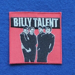 Op de afbeelding: Een vierkante geborduurde patch met een rode achtergrond en de tekst BILLY TALENT in witte letters op een zwarte rechthoekige balk. Onder de tekst staan vier figuren afgebeeld in zwart garen, zij aan zij in een groepsportret.