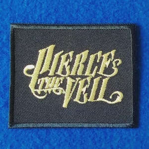Pode incluir: Um emblema retangular preto bordado com o texto Pierce The Veil numa fonte cursiva dourada estilizada. O emblema tem uma borda preta costurada e foi concebido para ser aplicado em artigos de tecido como casacos, malas ou vestuário.