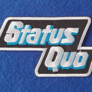 Könnte beinhalten: Ein rechteckiger gestickter Aufnäher mit schwarzem Hintergrund und weißem Rand. Der Text Status Quo ist in Weiß mit einem leuchtend blauen Schatteneffekt gestickt. Das Design ist in zwei Abschnitte unterteilt, Status oben und Quo unten rechts.