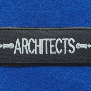 May include: A rectangular black embroidered patch featuring the word ARCHITECTS in white capital letters. The text is flanked on both sides by a white decorative horizontal emblem with a pointed end and a small circular detail.