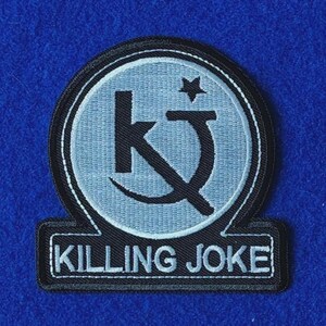 Könnte beinhalten: Ein kreisförmiger gestickter Aufnäher mit hellgrauem Hintergrund und einem schwarzen Logo, das aus den Buchstaben KJ und einem kleinen Stern besteht. Unter dem Kreis befindet sich eine rechteckige Lasche mit dem Text KILLING JOKE in weißen Buchstaben.