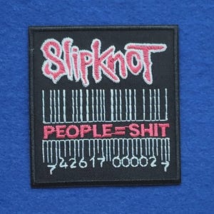 May include: A rectangular black embroidered patch featuring the pink Slipknot logo at the top. Below the logo is a white barcode graphic with the pink text PEOPLE=SHIT centred across it, followed by the numbers 42617 00002 at the bottom.