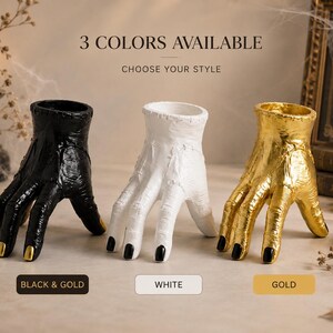 Puede incluir: Tres recipientes con forma de mano con piel texturizada y costuras visibles. El primero es negro con uñas pintadas de dorado, el segundo es blanco sólido con uñas negras y el tercero es dorado metálico con uñas negras. Texto: 3 COLORS AVAILABLE CHOOSE YOUR STYLE.