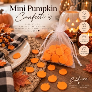 May include: A sheer white organza drawstring pouch filled with small, flat, orange pumpkin-shaped confetti pieces. Several individual orange pumpkin confetti pieces are scattered on the surface around the pouch, alongside artificial autumn leaves.