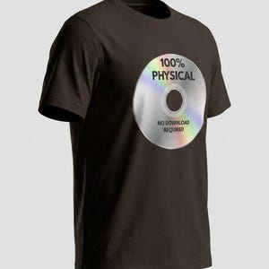 Pode incluir: Uma t-shirt de manga curta castanho-escura com um gráfico de um disco compacto prateado iridescente no peito. O disco tem o texto 100% PHYSICAL impresso acima do orifício central e NO DOWNLOAD REQUIRED impresso abaixo do orifício central.
